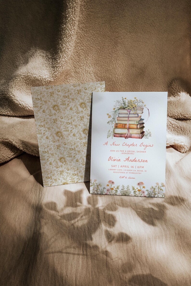 May include: A white invitation card with a floral border and a stack of books with flowers on top. The text on the card reads "A New Chapter Begins" and "Olivia Anderson".