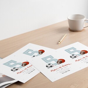 May include: Four printed invitations for a fifth birthday party, featuring a large blue number 5, a football, a soccer ball, and a basketball. The invitations are on a wooden table, with a white mug, a pen, and a coaster.