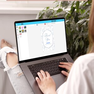 Op de afbeelding: Een laptop toont een ontwerp voor een babyborrel uitnodiging met de tekst "Thank You". Het scherm toont ook de tekst "DEMO BEFORE YOU BUY BY USING DEMO LINK IN LISTING DESCRIPTION". Een persoon gebruikt de laptop.