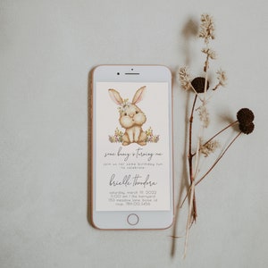 May include: A digital invitation with a cute cartoon bunny wearing a flower crown. The invitation says "Some bunny is turning one" and includes details for a birthday party.