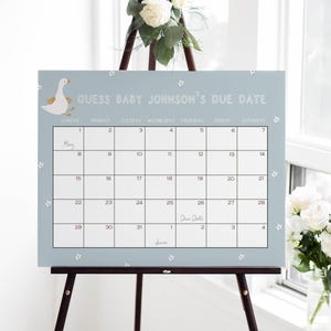 May include: A light blue calendar with white flowers printed on it. The calendar is titled "Guess Baby Johnson's Due Date" and has the month of May with the due date marked on the 26th.