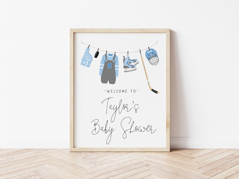 Pode incluir: Um cartaz branco com um an&uacute;ncio de ch&aacute; de beb&ecirc; de h&oacute;quei em azul e cinza. O cartaz diz "Bem-vindo ao ch&aacute; de beb&ecirc; de Taylor".