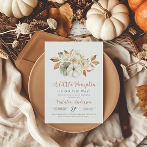 Op de afbeelding: Een uitnodiging voor een babyshower met de tekst "A Little Pumpkin - Is on the Way-". De uitnodiging bevat aquarel pompoenen en bloemstukken in tinten wit, groen en oranje. De datum is 27 oktober om 11:00 uur.