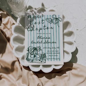 Pu&ograve; includere: Un invito a righe blu e bianche con il testo "Her Next Chapter" e "Olivia's Bridal Shower". L'invito include la data, l'ora, il luogo e le informazioni di registrazione.