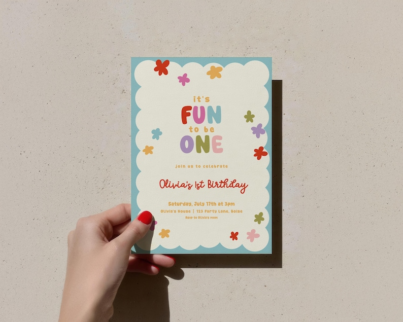 May include: A colorful birthday invitation with a light blue scalloped border. The text "It's FUN to be ONE" is displayed in vibrant colors. The invitation also includes the text "Olivia's 1st Birthday" and event details. Floral accents are scattered around the design.