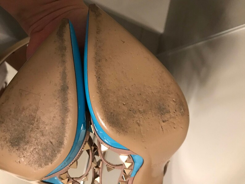 Puede incluir: Un par de zapatos de tac&oacute;n alto con suela de cuero marr&oacute;n claro y ribete azul. Los zapatos tienen un dise&ntilde;o de tachuelas en la parte delantera.