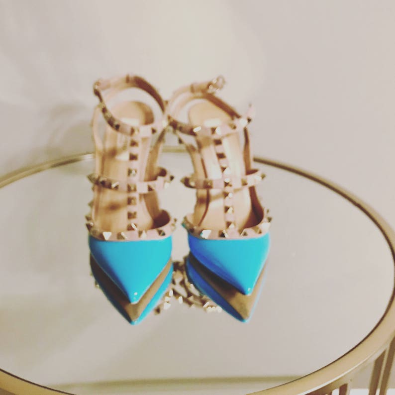 Puede incluir: Un par de zapatos de tac&oacute;n alto azules y nude con un dise&ntilde;o de tachuelas.