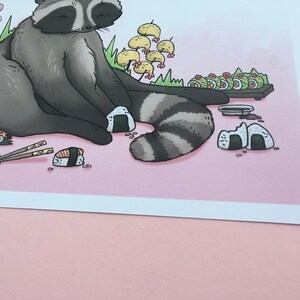May include: A cartoon raccoon sitting on a pink background with a plate of sushi, chopsticks, and rice balls. The raccoon is wearing a contented expression.