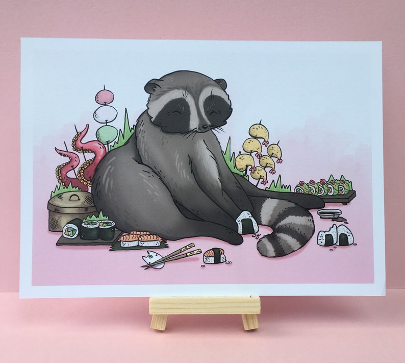 May include: A cartoon raccoon sitting on a pink background surrounded by sushi, a bowl of noodles, and other Japanese-inspired decorations.