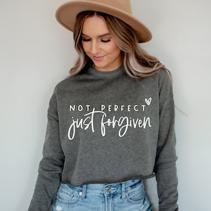 May include: A gray cropped sweatshirt with the text "NOT PERFECT just forgiven" and a small heart symbol.