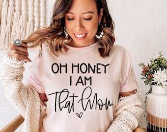Puede incluir: Una camiseta rosa con el texto "Oh honey I am that mom" en letras negras.