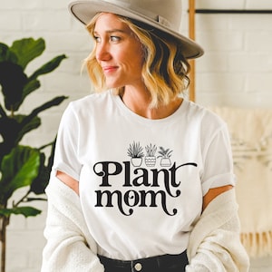 May include: A white t-shirt with a black graphic of potted plants and the text "Plant mom".