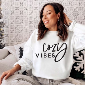 May include: White sweatshirt with black text that reads "cozy vibes".