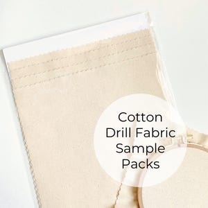 May include: A clear plastic package containing several rectangular samples of beige cotton drill fabric. The text "Cotton Drill Fabric Sample Packs" is overlaid on the image. An embroidery hoop is partially visible.