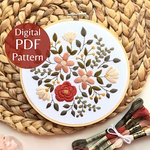 Könnte beinhalten: Ein Blumenstickmuster in einem Holzreifen. Das Design zeigt pfirsichfarbene, cremefarbene und rote Blumen mit grünen Blättern. Der Text "Digital PDF Pattern" befindet sich in einem roten Kreis. Stickgarn in passenden Farben befindet sich unten.