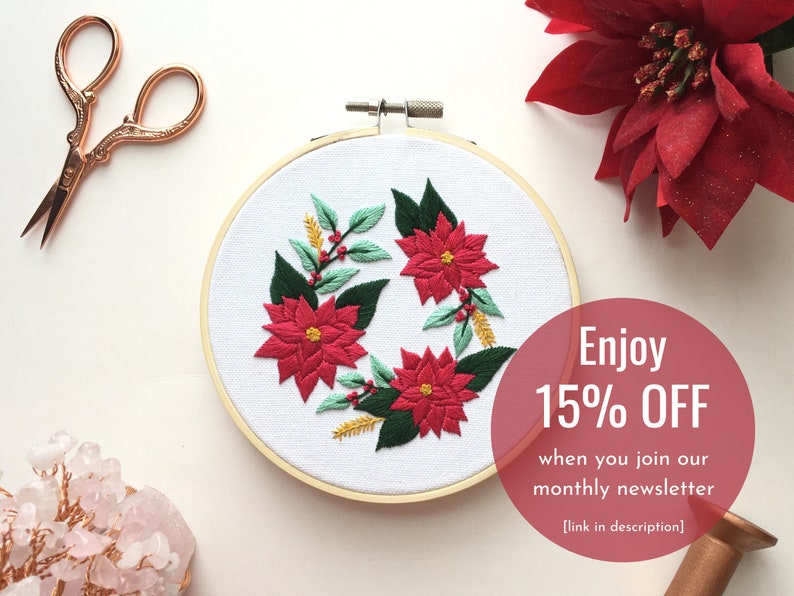 May include: Embroidered hoop art featuring a wreath of poinsettia flowers and greenery. The hoop is wooden and the background is white. The text "Enjoy 15% OFF when you join our monthly newsletter [link in description]" is visible in the lower right corner.