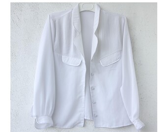 May include: A white long-sleeved button-up shirt with a pleated detail on the front and two flap pockets.