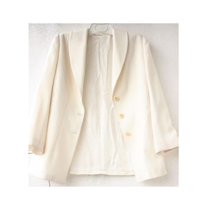 May include: A white blazer with a shawl collar and three buttons. The blazer is made of a smooth fabric and has a classic, tailored look.