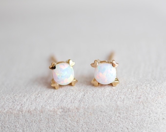 May include: A pair of gold stud earrings with white opal stones.