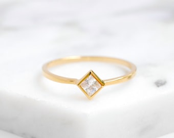 May include: A gold ring with a square-shaped clear gemstone.
