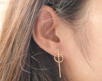 May include: Gold earrings with a thin vertical bar and a small circle.