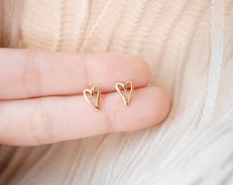Puede incluir: Un par de pendientes de corazón de oro. Los pendientes son simples y delicados, con un diseño de alambre fino.
