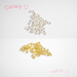 Puede incluir: Dos montones de piedras de cristal sueltas, facetadas, redondas y transparentes. El mont&oacute;n superior est&aacute; etiquetado como "Canary" y es blanco. El mont&oacute;n inferior est&aacute; etiquetado como "Yellow" y es de color amarillo claro.