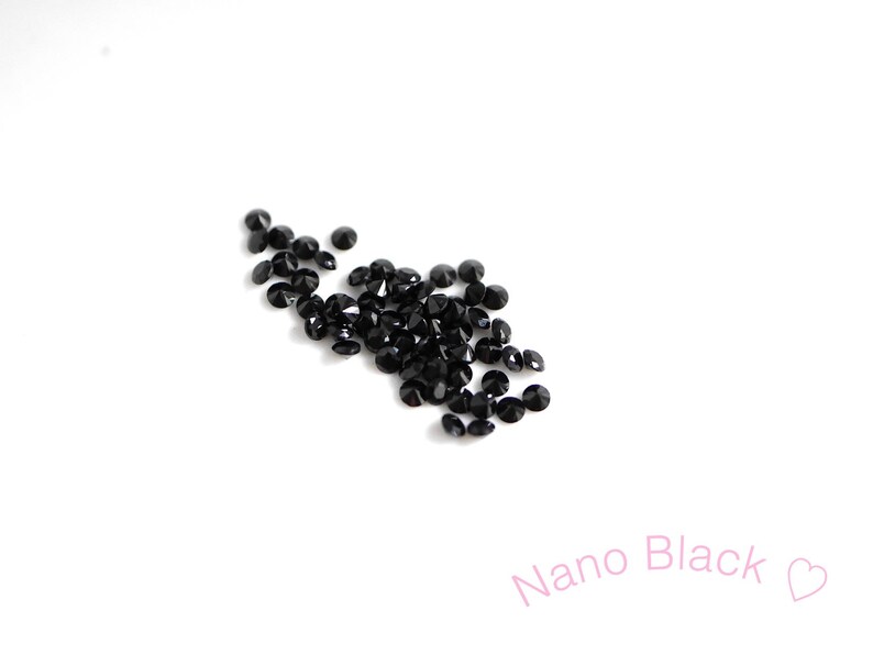 Puede incluir: Una dispersi&oacute;n de peque&ntilde;os diamantes de imitaci&oacute;n redondos negros sobre un fondo blanco. Nano Black.