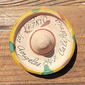 May include: A small, round, ceramic sombrero with green and yellow accents. It says "Los Angeles, 1948, Cal. California" in handwritten script.