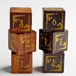 May include: Six wooden dice with gold-coloured numbers and decorative corner designs. The dice are stacked in two columns, with numbers 1 to 7 visible. The wood has a dark brown and reddish-brown colour.