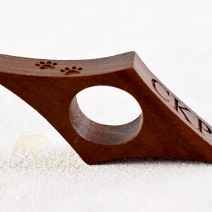 May include: A brown wooden bookmark with a paw print design and the initials "CKP" engraved on the side.