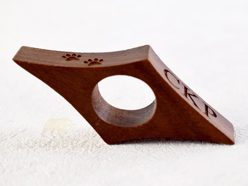 May include: A brown wooden bookmark with a paw print design and the initials "CKP" engraved on the side.