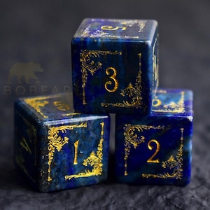 Peut inclure: Trois d&eacute;s bleus avec des filigranes dor&eacute;s et des chiffres. Les d&eacute;s sont empil&eacute;s, affichant les chiffres 1, 2 et 3. Les d&eacute;s ont un fond bleu fonc&eacute; et des accents dor&eacute;s. Id&eacute;al pour les jeux de soci&eacute;t&eacute;.