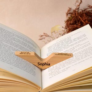 Peut inclure: Un support de livre en bois avec les mots "Book Whore" et "Spread Those Pages" grav&eacute;s dessus. Le support maintient un livre ouvert avec le nom "Sophia" grav&eacute; sur la pi&egrave;ce centrale.