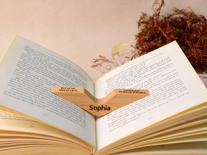 Peut inclure: Un support de livre en bois avec les mots "Book Whore" et "Spread Those Pages" grav&eacute;s dessus. Le support maintient un livre ouvert avec le nom "Sophia" grav&eacute; sur la pi&egrave;ce centrale.