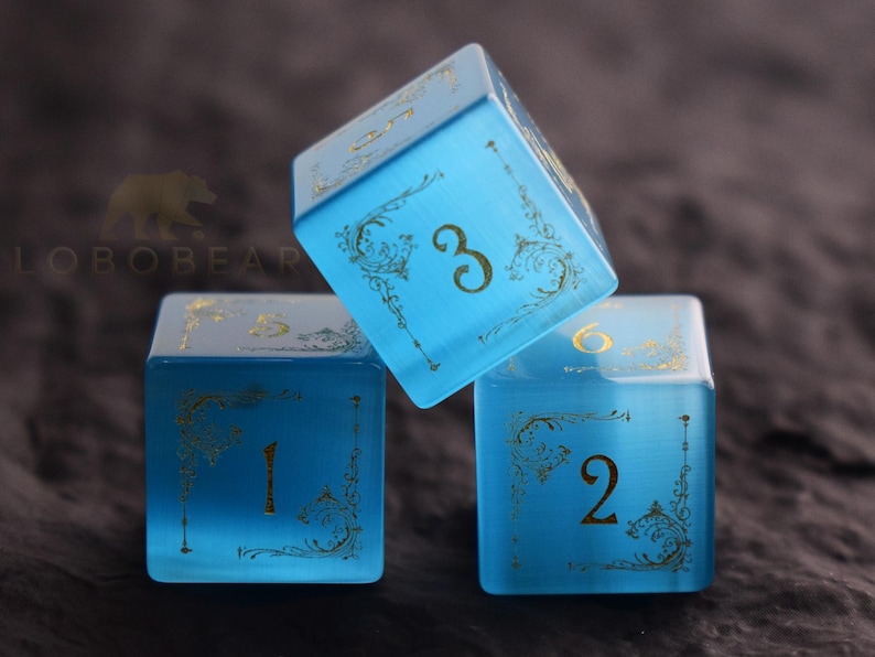 Peut inclure: Trois d&eacute;s bleus translucides avec des chiffres dor&eacute;s et des filigranes d&eacute;coratifs. Les d&eacute;s sont dispos&eacute;s de mani&egrave;re dynamique, avec un d&eacute; inclin&eacute;. Les chiffres 1, 2, 3 et 6 sont visibles. D&eacute;s pour jeux de soci&eacute;t&eacute;.