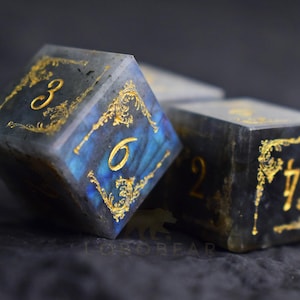 Peut inclure: Gros plan sur trois d&eacute;s &agrave; l'aspect sombre et marbr&eacute;. Les d&eacute;s ont des chiffres dor&eacute;s et des motifs de filigrane dor&eacute;s orn&eacute;s sur chaque face. Les chiffres 3, 6, 2 et 7 sont visibles. Les d&eacute;s sont pour les jeux de soci&eacute;t&eacute;.