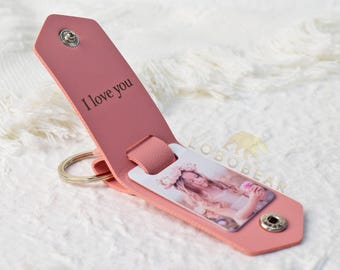May include: A pink leather keychain with a photo insert and a metal ring. The keychain has the words "I love you" engraved on the front.