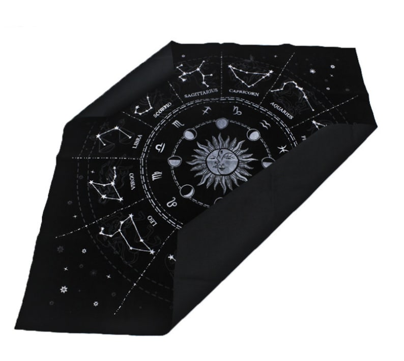 May include: Black velvet cloth with a white zodiac wheel design featuring the constellations and astrological symbols. The cloth is folded in half, revealing the black velvet backing.