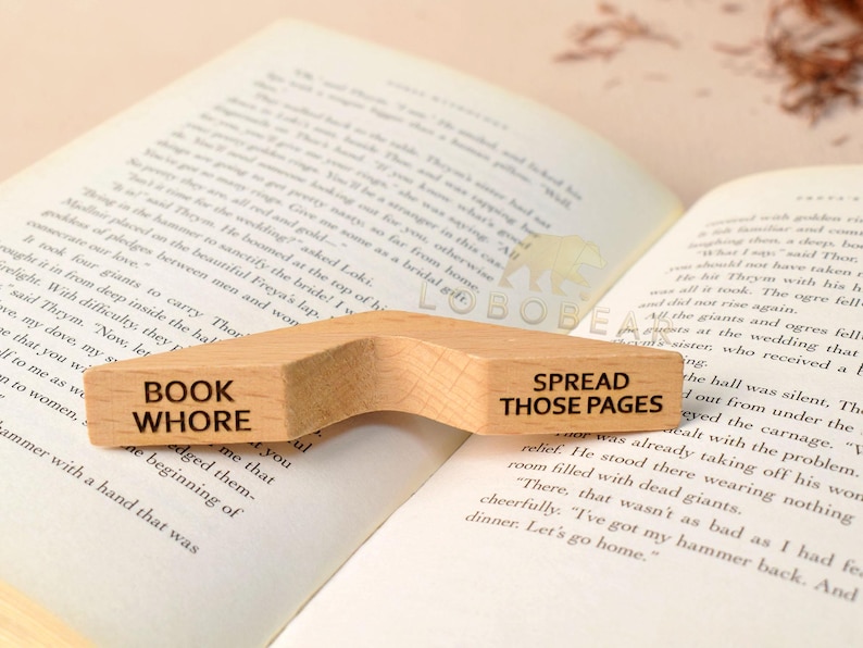 Peut inclure: Un serre-livres en bois avec une forme incurv&eacute;e. Le c&ocirc;t&eacute; gauche dit "Book Whore" et le c&ocirc;t&eacute; droit dit "Spread Those Pages".