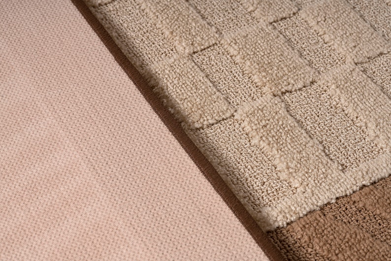 Pode incluir: Close-up de dois tecidos com texturas diferentes. Um &eacute; um tecido rosa claro com um padr&atilde;o tecido sutil. O outro &eacute; um tecido bege com um padr&atilde;o quadriculado em relevo.