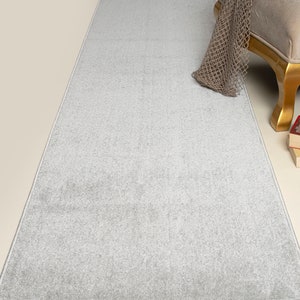 May include: A light gray runner rug with a subtle texture. The rug is placed on a light beige floor and has a white border.
