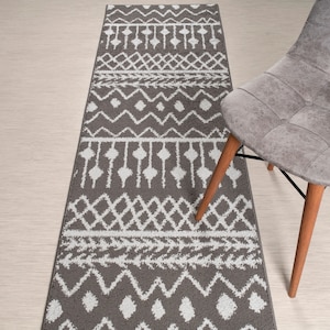 May include: A gray and white runner rug with a geometric pattern. The rug has a fringe border and is made of a soft, plush material.