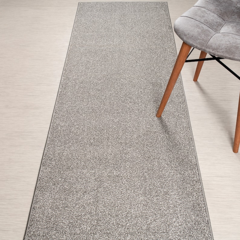 May include: A gray and white runner rug with a textured surface. The rug is made of a soft, plush material and has a subtle sheen.