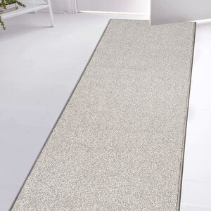 May include: A light gray runner rug with a subtle textured pattern. The rug is placed in front of a white door.