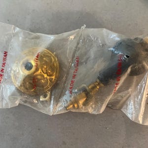 May include: Two gold-toned door knobs in a clear plastic bag. The knobs have a decorative design and are labeled "Made in Taiwan".