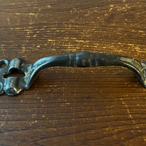 May include: A black metal door handle with a decorative design and a keyhole.
