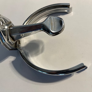 May include: A chrome-plated metal ring holder with a lever to open and close the ring. The holder is designed to be mounted on a wall.