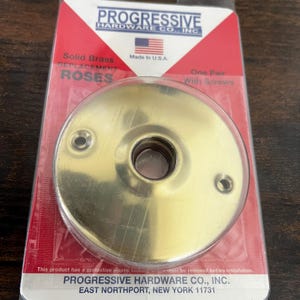 May include: A solid brass replacement rose, packaged in a clear plastic wrap. The packaging features the "PROGRESSIVE HARDWARE CO., INC." logo, the American flag, and the text "Made in U.S.A."
