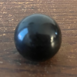 May include: A black, round, smooth, and shiny sphere.